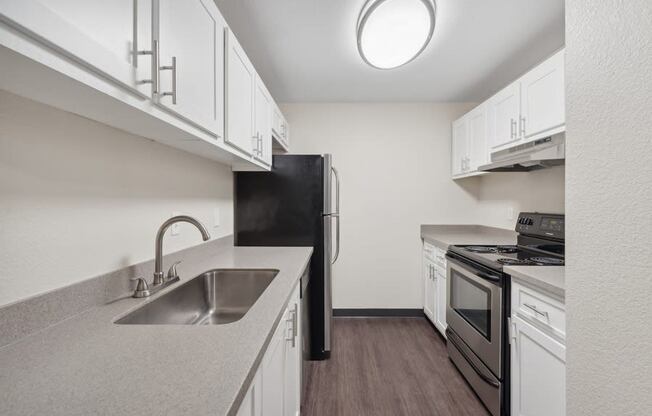 a kitchen with white cabinets and a sink and a black refrigerator