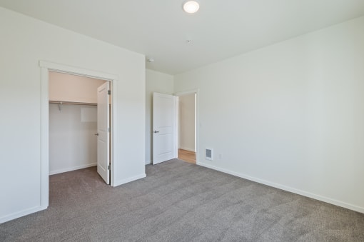 a bedroom with white walls and carpet and a door to a closet at Gateway Apartments, East Wenatchee , WA