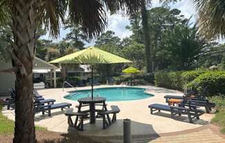 A pool surrounded by trees and a picnic table.