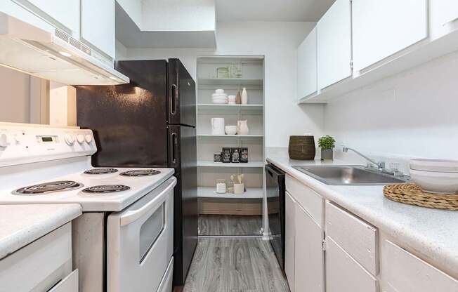 A modern kitchen with white appliances and a black refrigerator.