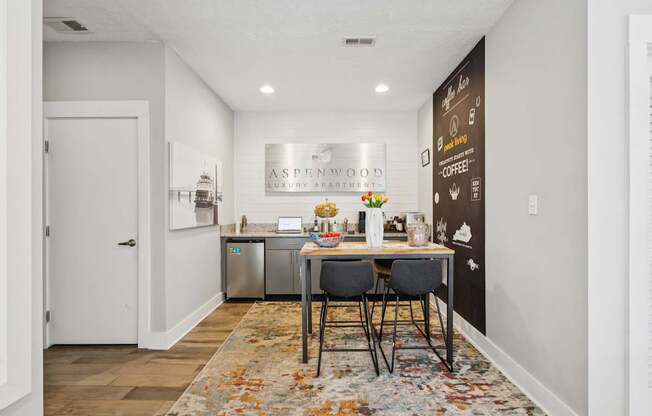 A kitchen area with a table and chairs in front of a chalkboard wall.