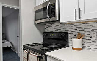 A kitchen with a black stove top oven and a black microwave above it.