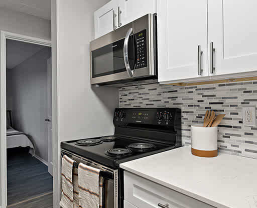 A kitchen with a black stove top oven and a black microwave above it.