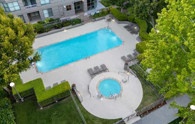 A swimming pool surrounded by a grassy area and trees.