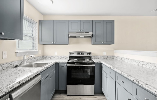 a kitchen with gray cabinets and white counter tops and a stove and sink at Diamond Ridge Townhomes, Oklahoma City Oklahoma