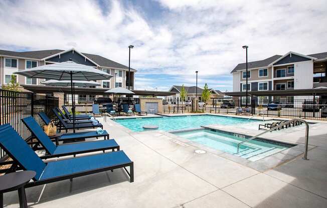 A pool area with sun loungers and a building in the background.