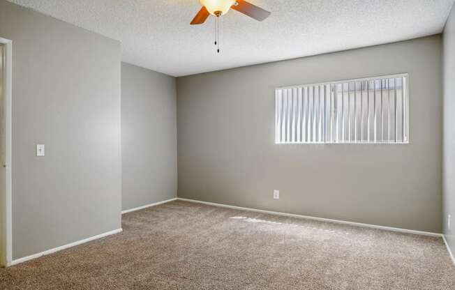 an empty living room with a ceiling fan and a window