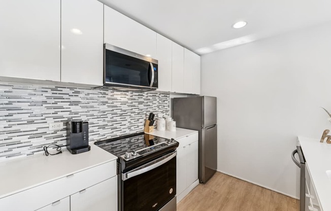A modern kitchen with a black and white tile backsplash and stainless steel appliances.