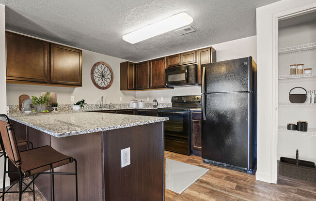 A kitchen with a black refrigerator and brown cabinets.