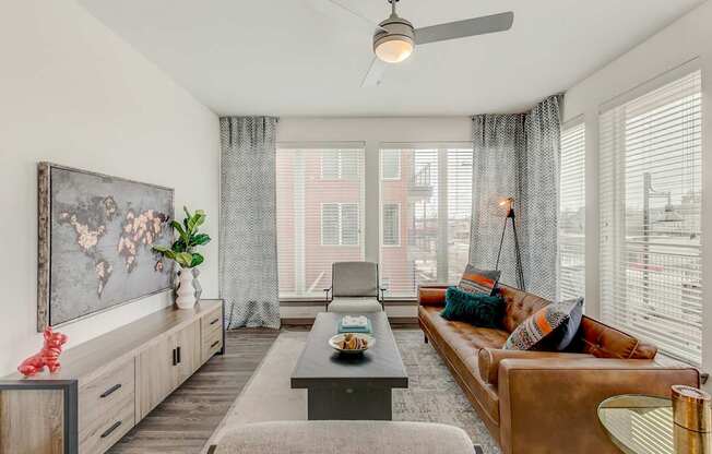 A living room with a brown couch, a coffee table, and a painting on the wall.