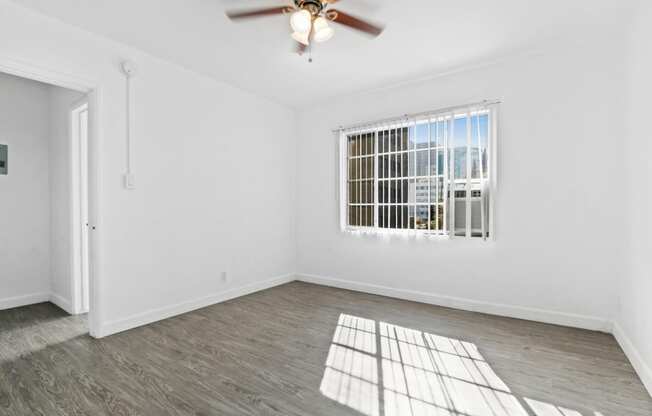 an empty living room with a window and a ceiling fan