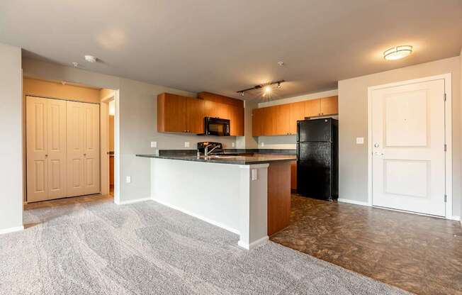 A kitchen with a black refrigerator and wooden cabinets.