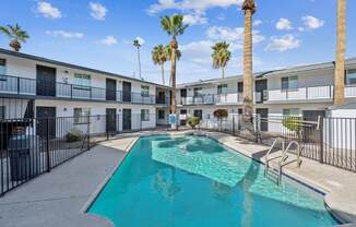 A swimming pool in front of a building with palm trees.