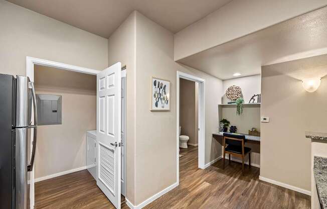 A kitchen area with a refrigerator, a table, and a chair.at The Equestrian by Picerne, Henderson
