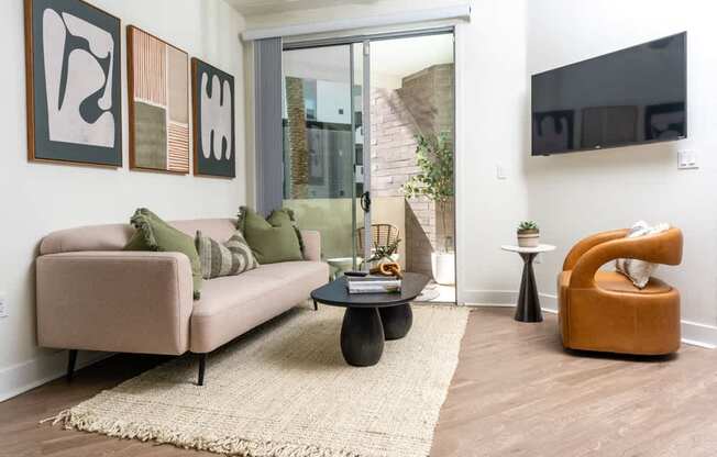 A living room with a beige couch, a coffee table, and a TV mounted on the wall.