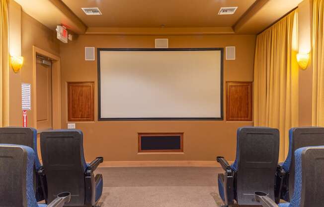 a theater room with chairs and a large screen