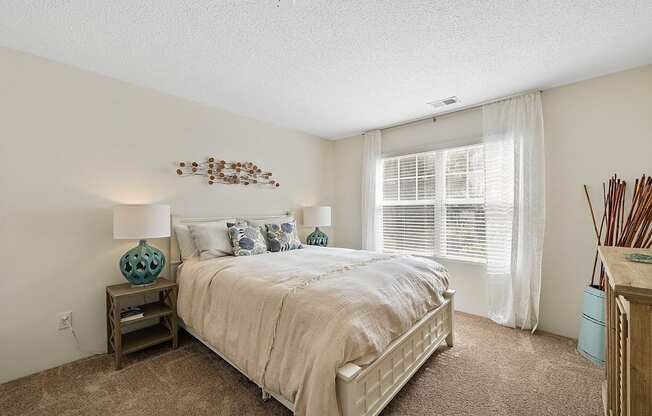 A bedroom with a large bed and a wooden nightstand.
