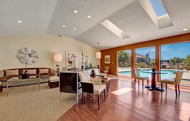 A spacious resident lounge here at Cypress Pointe with modern décor, comfortable seating, and warm wood-style flooring creating a welcoming atmosphere. An open layout with decorative accents, soft lighting, and views into adjacent gathering areas offers an inviting space for relaxing or socializing.