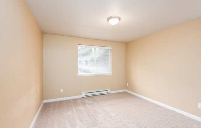 an empty room with beige walls and a window