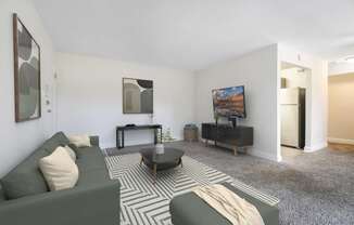 A living room with a green couch, a coffee table, and a painting on the wall.