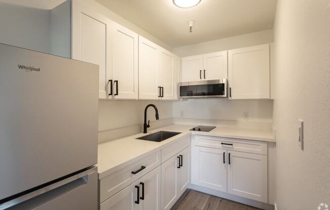 a kitchen with white cabinets and a sink and a refrigerator