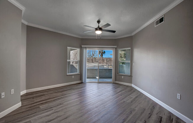 a living room with a ceiling fan and a door to a balcony