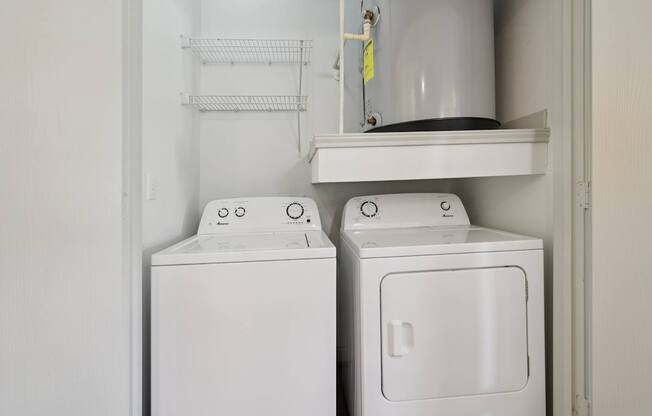 Two white washing machines in a small laundry room.