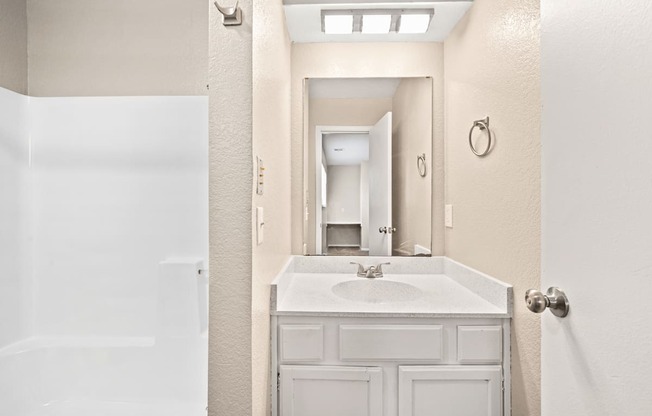 a bathroom with a sink and a mirror and a shower at Diamond Ridge Townhomes, Oklahoma City