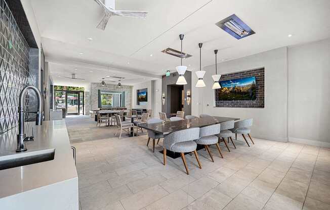 Clubroom with a long dining table, plush seating, and entertainment screens designed for community gatherings