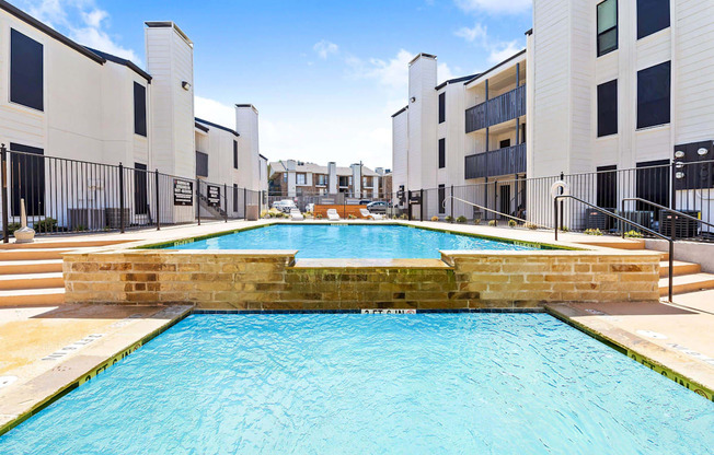 a large swimming pool with apartments in the background