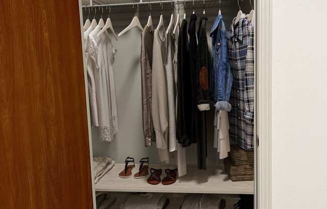 a walk in closet with white shelves and a wooden door