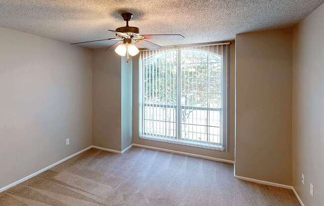 a bedroom with a large window and a ceiling fan