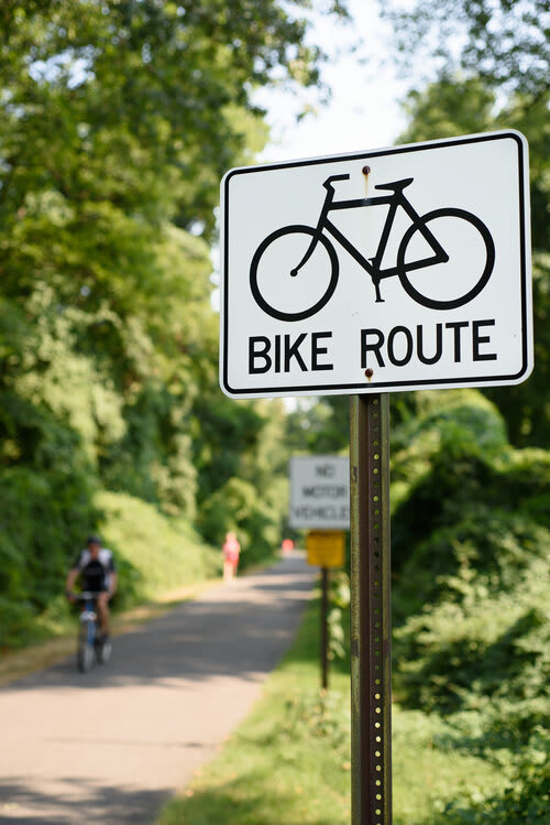 a white bike route sign sitting on the side of a road