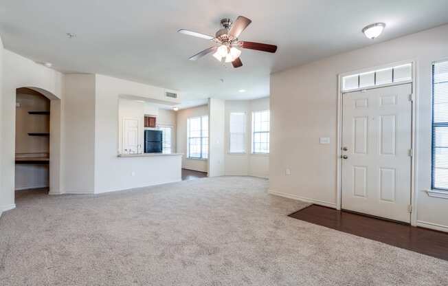 an empty living room with a ceiling fan