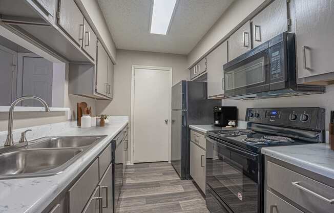 A kitchen with a black stove top oven and a black microwave above it.