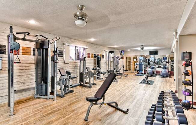 a gym with cardio machines and weights on a wooden floor