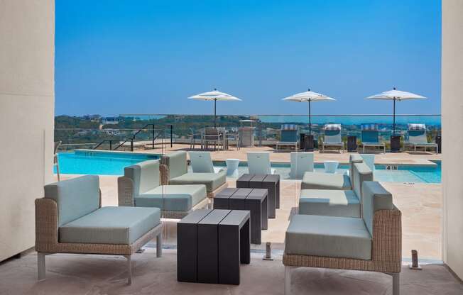 a poolside seating area with blue chairs and umbrellas at a resort