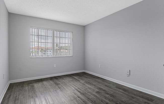 the spacious living room with wood flooring and a window