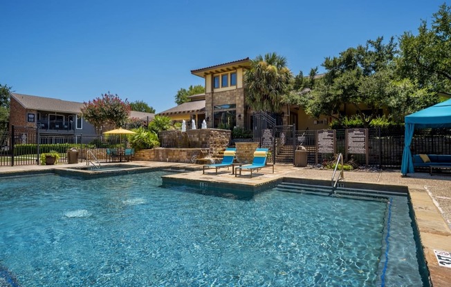 Resort-style pool with tanning ledge, lounge chairs, and landscaped courtyard views.