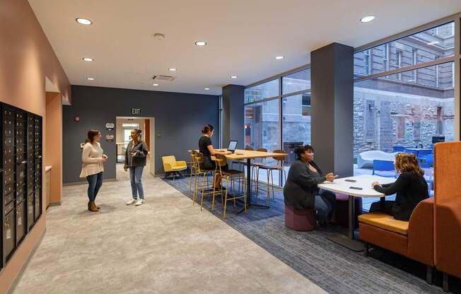 A group of people are gathered in a room with a large window.