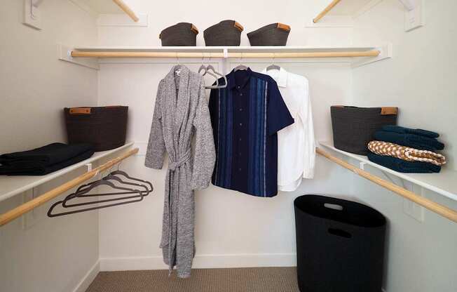 a walk in closet with wooden shelves and racks with clothes and baskets