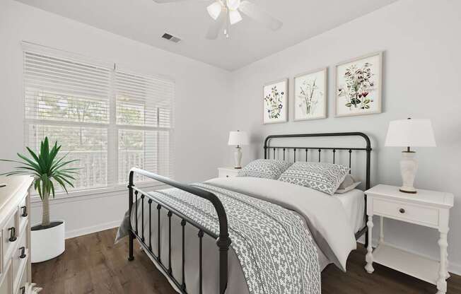 A bedroom with a bed, nightstand, and a plant.