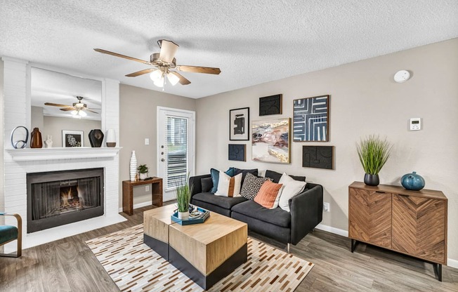 an open living room with a fireplace and a ceiling fan