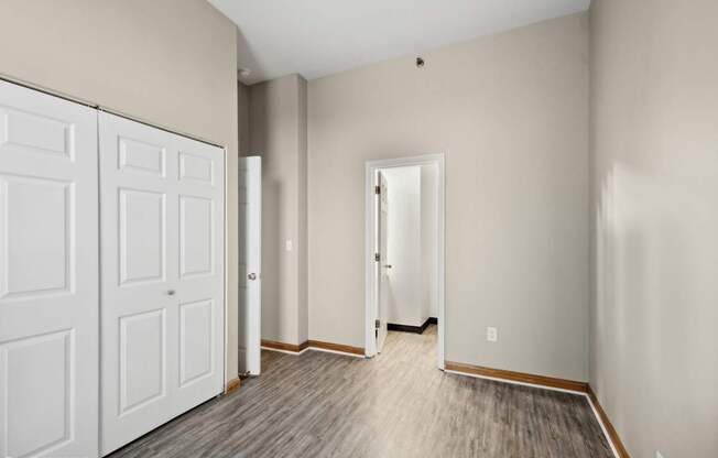 an empty bedroom with white doors and wood flooring