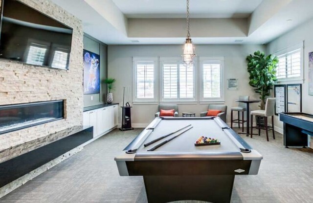 Game room with billiards table, shuffleboard, flat screen television, and fireplace