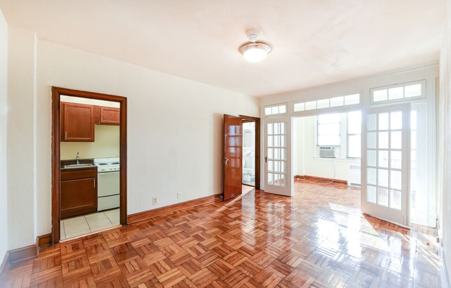 vacant living area with large windows, hard wood flooring and view of kitchen and sunroom at eddystone apartments in washington dc