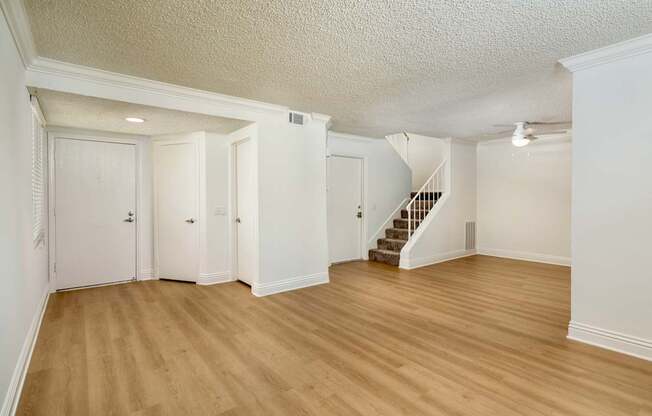 A spacious living room with wooden floors and white walls.