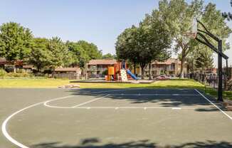 basketball court with playground and trees in the background