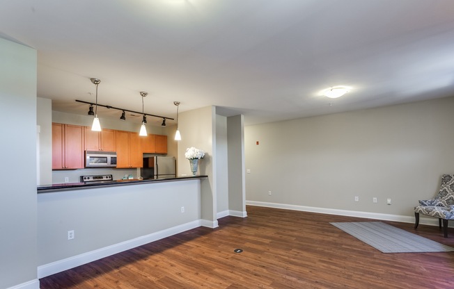 View of Living Room, Showing Plank-Wood Flooring, Breakfast Bar, and View of Kitchen at Alpha Mill Apartments