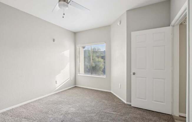 A room with a ceiling fan and a door.